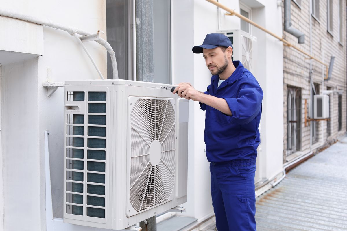 An HVAC technician servicing an outdoor unit